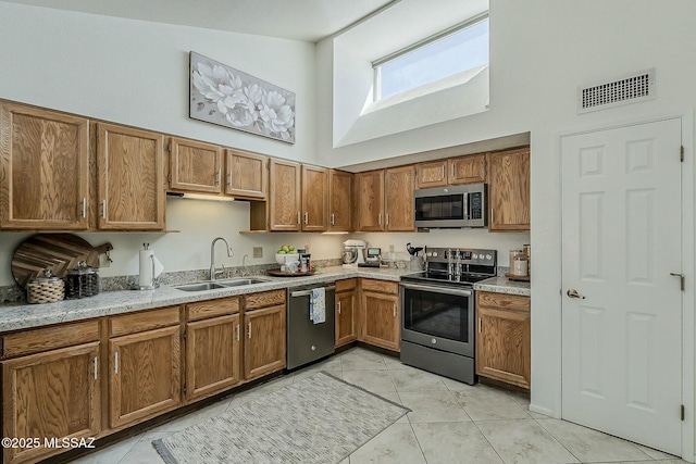 kitchen featuring brown cabinets, visible vents, appliances with stainless steel finishes, and a sink