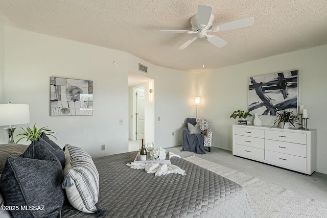 bedroom with light carpet, visible vents, a textured ceiling, and ceiling fan