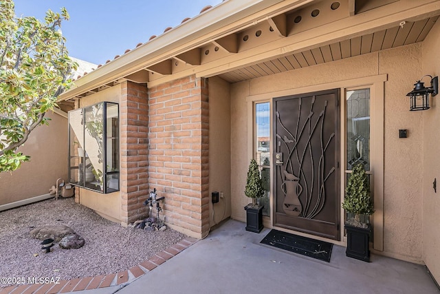 entrance to property featuring stucco siding and brick siding