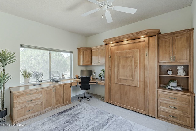 home office featuring light tile patterned floors, a ceiling fan, built in desk, and a textured ceiling