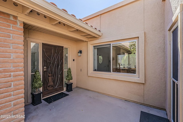 view of exterior entry featuring a patio area and stucco siding