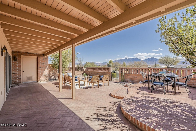 view of patio / terrace with outdoor dining space, fence, visible vents, an outdoor living space, and a mountain view