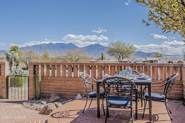 view of patio featuring outdoor dining area, a mountain view, and fence