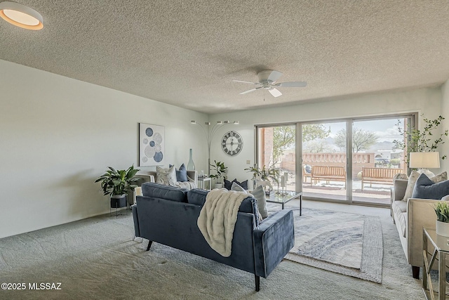 carpeted living room with a textured ceiling and a ceiling fan