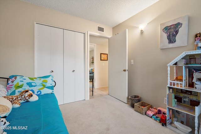 bedroom with light carpet, a closet, and a textured ceiling