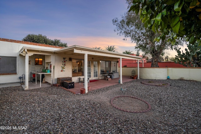 back house at dusk featuring a patio area