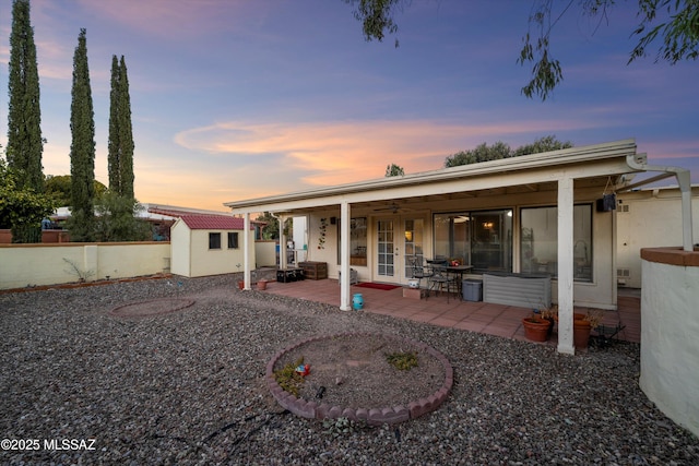 back house at dusk with a storage unit and a patio area