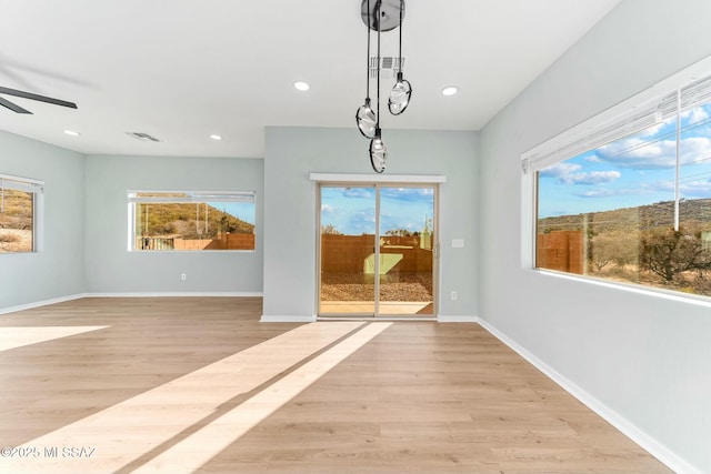 unfurnished dining area featuring light wood-type flooring, plenty of natural light, and baseboards