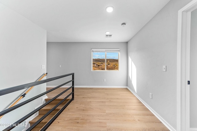unfurnished room featuring visible vents, light wood-style flooring, and baseboards