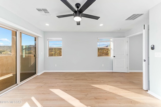 spare room featuring light wood-type flooring, visible vents, and baseboards