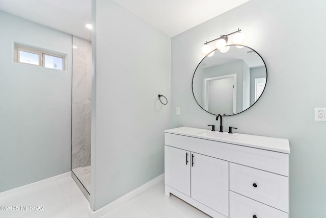 bathroom with tile patterned flooring, baseboards, tiled shower, and vanity