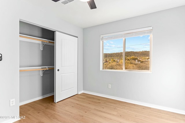 unfurnished bedroom featuring a closet, visible vents, a ceiling fan, wood finished floors, and baseboards