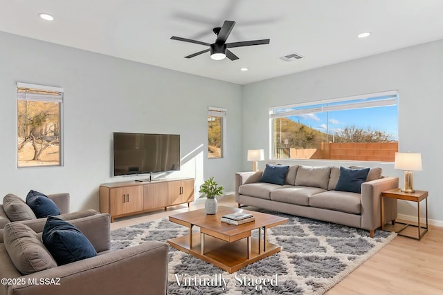 living room featuring baseboards, light wood-type flooring, visible vents, and recessed lighting