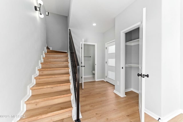 stairs with baseboards, wood finished floors, and recessed lighting