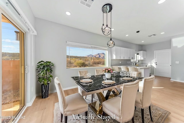 dining area with light wood-style flooring, visible vents, and a wealth of natural light