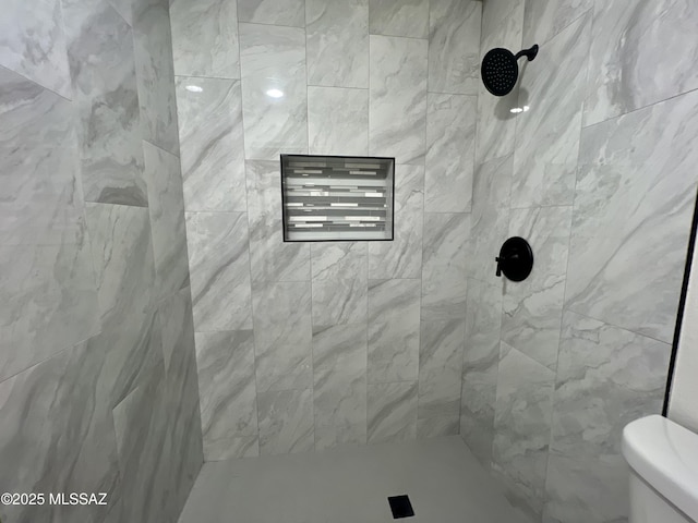 bathroom with a tile shower and toilet