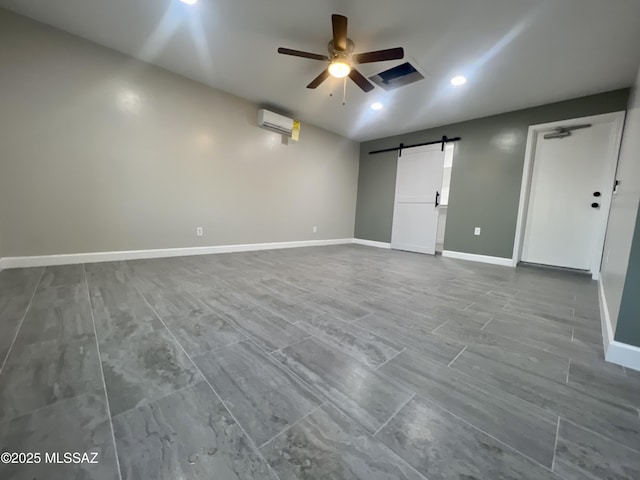 empty room with ceiling fan, a barn door, and an AC wall unit