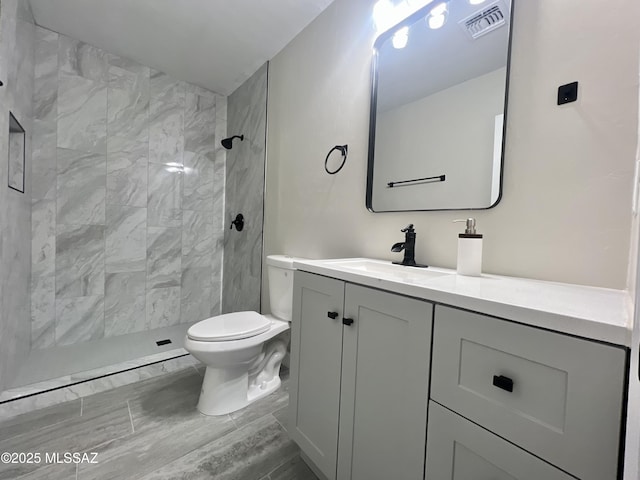 bathroom with vanity, toilet, and a tile shower