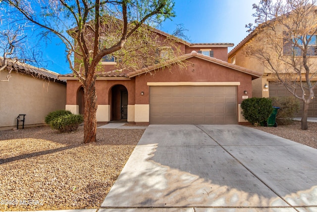 mediterranean / spanish house with driveway, an attached garage, a tile roof, and stucco siding