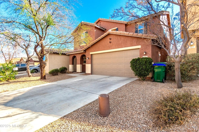 mediterranean / spanish home featuring a garage, concrete driveway, a tiled roof, and stucco siding