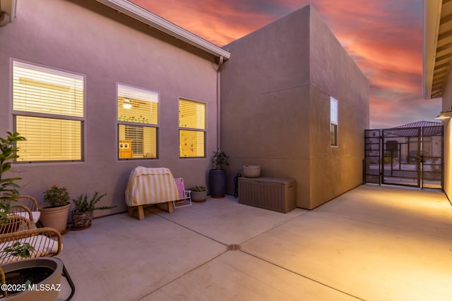 back house at dusk featuring a patio