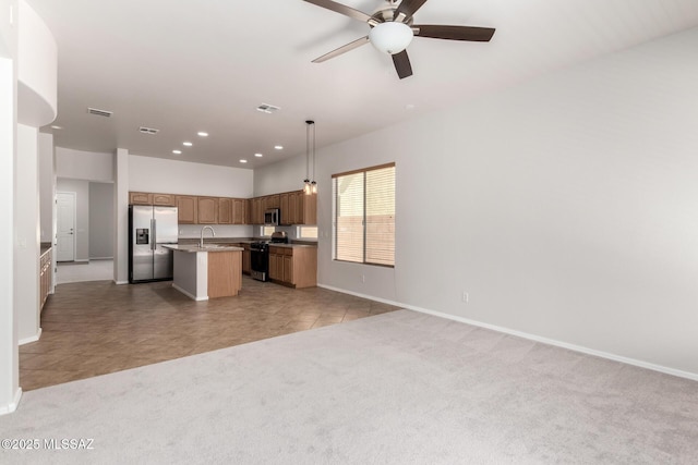 kitchen with sink, light carpet, hanging light fixtures, a center island with sink, and stainless steel appliances