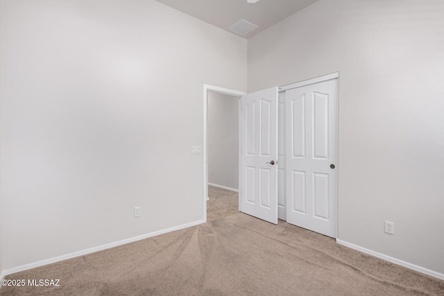 unfurnished bedroom with light carpet and a closet