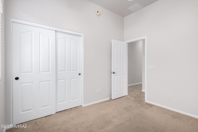 unfurnished bedroom featuring light carpet and a closet