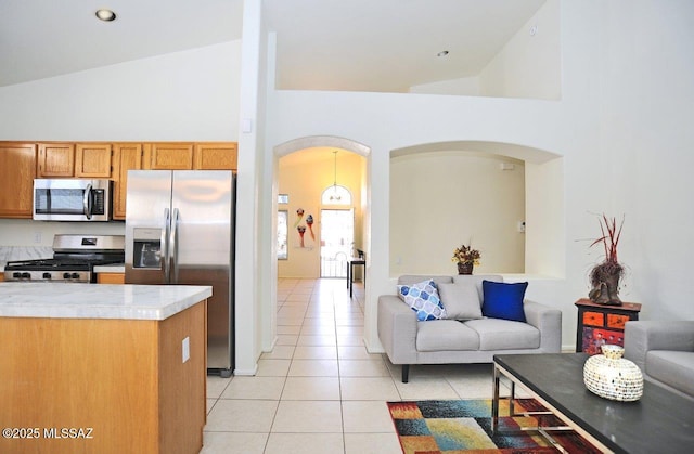 kitchen featuring light tile patterned floors, high vaulted ceiling, and appliances with stainless steel finishes