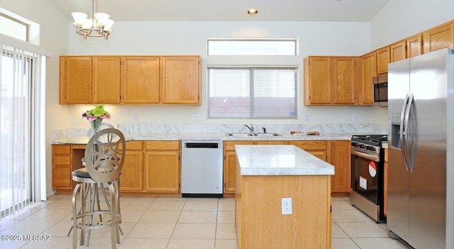 kitchen with appliances with stainless steel finishes, pendant lighting, sink, a center island, and light tile patterned floors