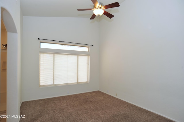 carpeted spare room featuring a towering ceiling and ceiling fan