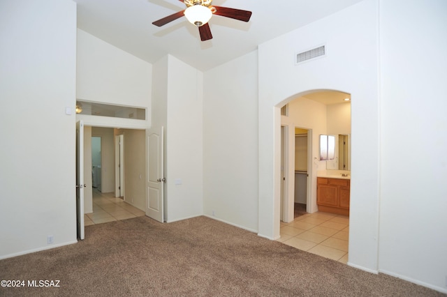 spare room featuring light colored carpet, ceiling fan, and a high ceiling