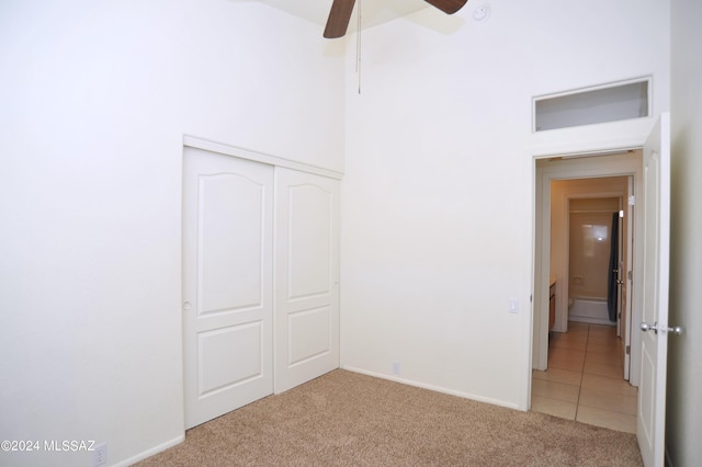 unfurnished bedroom featuring ceiling fan, a closet, and light carpet