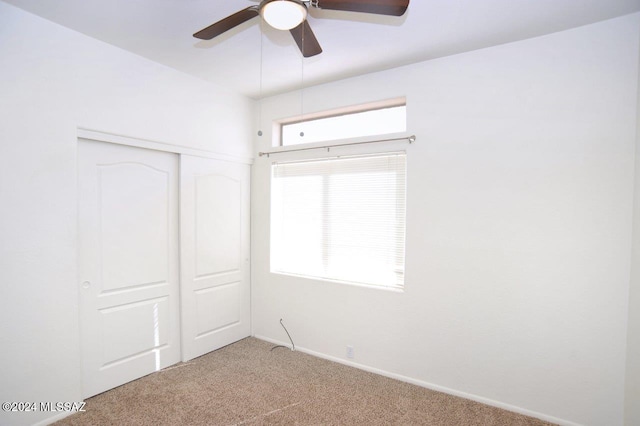 unfurnished bedroom featuring multiple windows, carpet floors, ceiling fan, and a closet