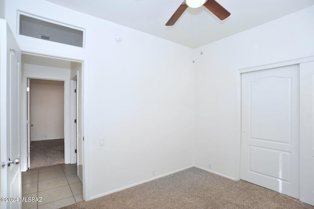 unfurnished bedroom featuring light colored carpet, ceiling fan, and a closet