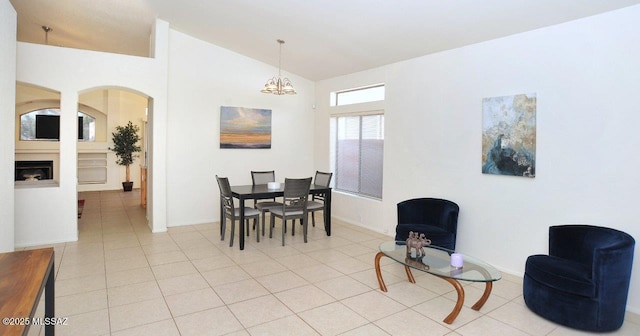 dining area with lofted ceiling, light tile patterned floors, and a notable chandelier