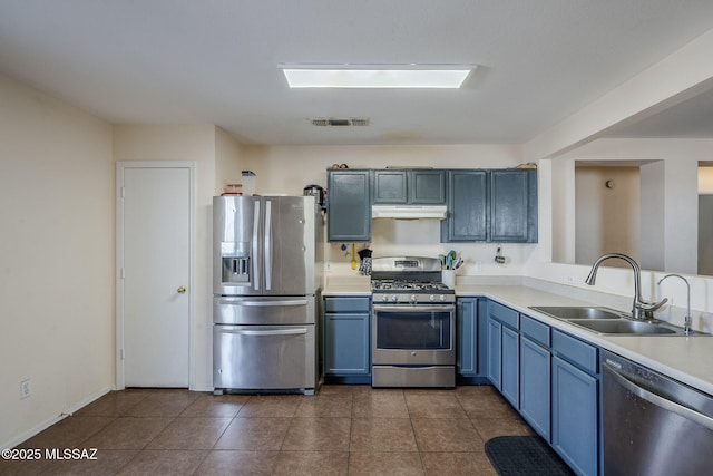 kitchen featuring blue cabinetry, stainless steel appliances, dark tile patterned flooring, and sink