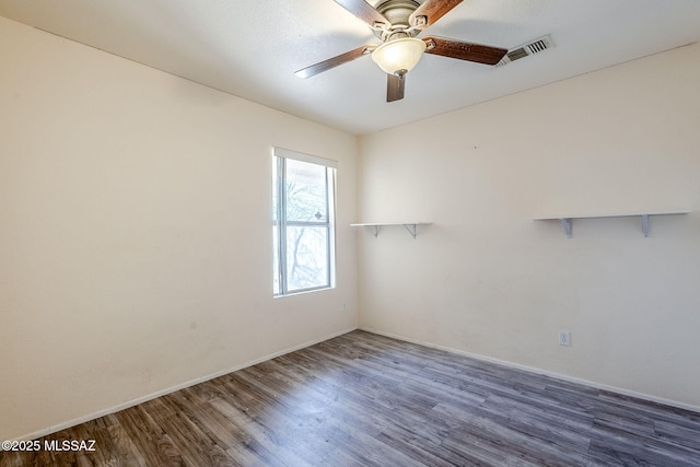 spare room with dark hardwood / wood-style flooring and ceiling fan