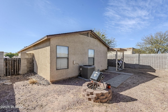 rear view of house featuring a fire pit and central AC