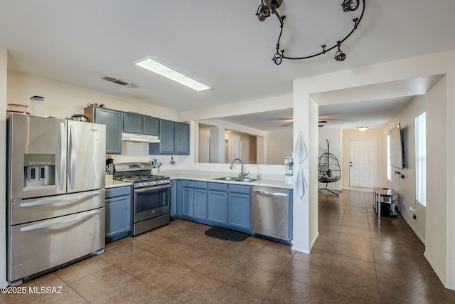 kitchen with stainless steel appliances, blue cabinets, sink, and dark tile patterned floors