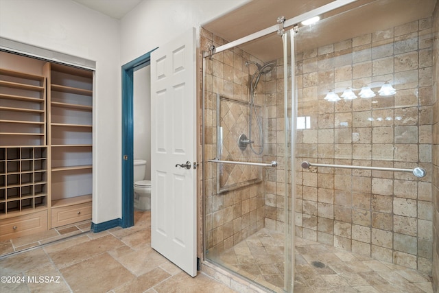 bathroom featuring a walk in closet, stone finish flooring, a shower stall, and toilet