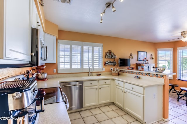 kitchen featuring sink, light tile patterned floors, ceiling fan, stainless steel appliances, and kitchen peninsula