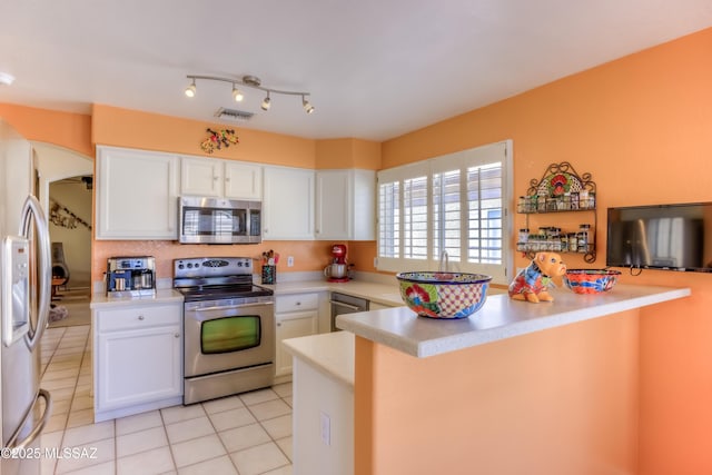 kitchen with stainless steel appliances, white cabinetry, light tile patterned floors, and kitchen peninsula