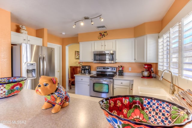 kitchen with plenty of natural light, appliances with stainless steel finishes, sink, and white cabinets