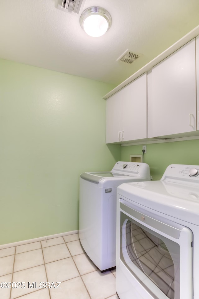 laundry room featuring cabinets, light tile patterned floors, and washing machine and clothes dryer