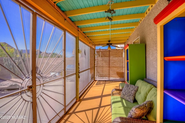 unfurnished sunroom with beam ceiling and ceiling fan