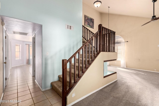 stairs with tile patterned flooring and a towering ceiling