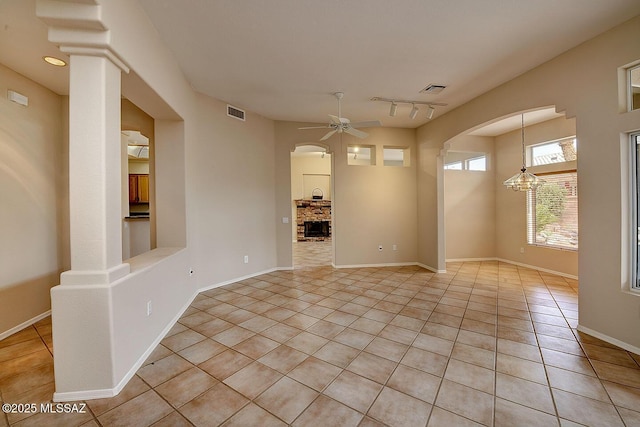 14686 N Lost Arrow Dr, Oro Valley, AZ 85755 - empty room with a fireplace, rail lighting, ceiling fan with notable chandelier, and light tile patterned floors