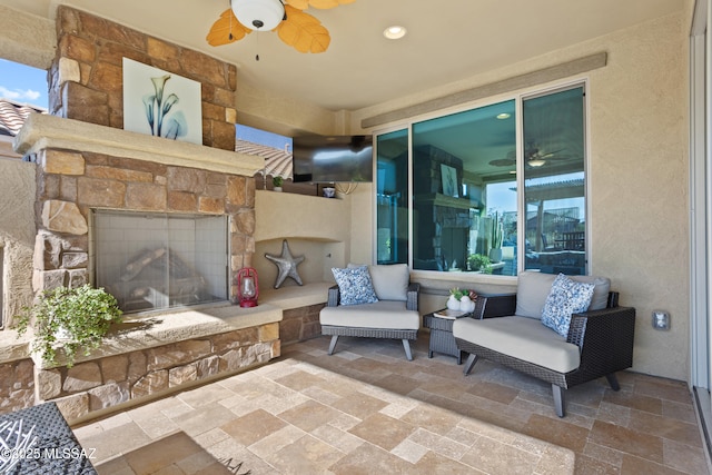 view of patio with a ceiling fan and an outdoor stone fireplace