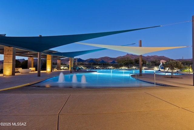 pool at dusk featuring a mountain view and a community pool